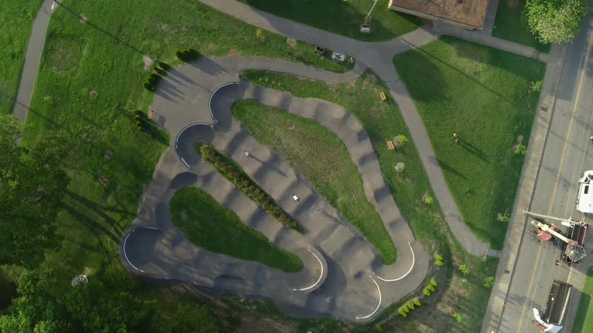 A birds eye view of two bicyclists speeding along a challenging terrain in a bike park in the daytime