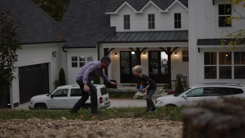 Father and son play ball on the front yard in the neighborhood