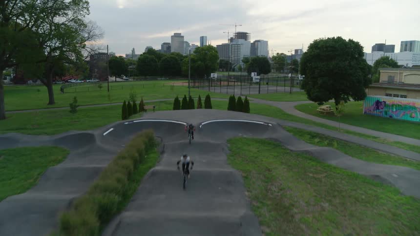 Two cyclists jumping and driving motocross bicycles on a beautiful small track on a park