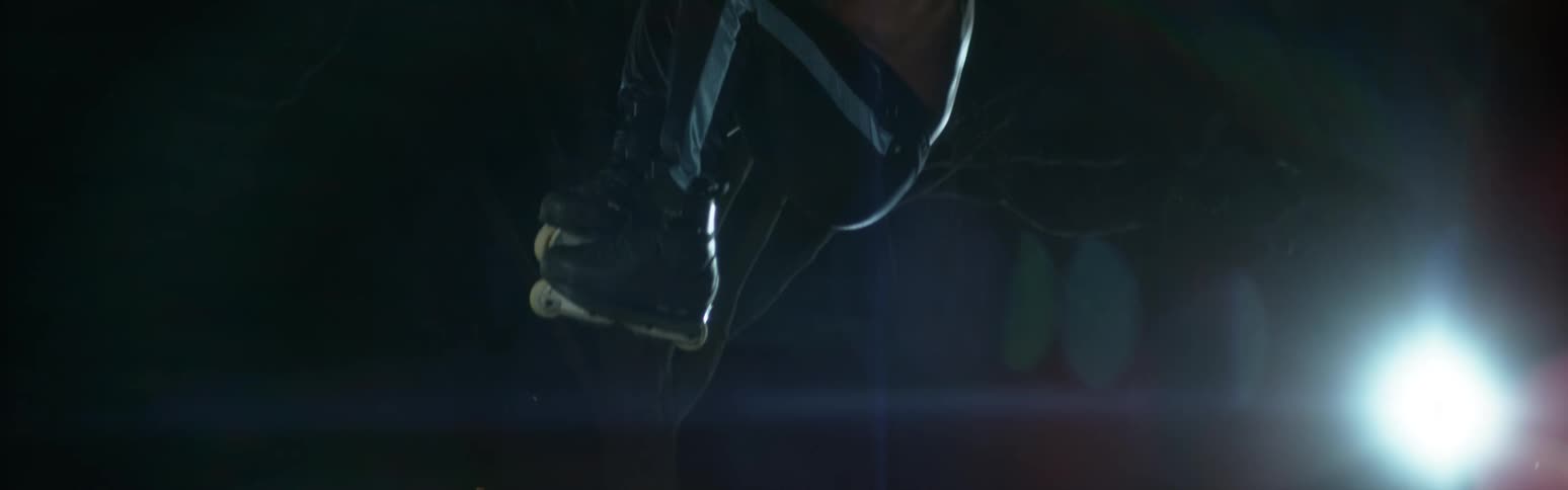 Young muscular shirtless man wearing roller skates jumping at night