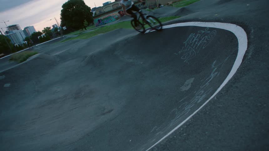 Cyclist rides along rim of concrete bowl in city park