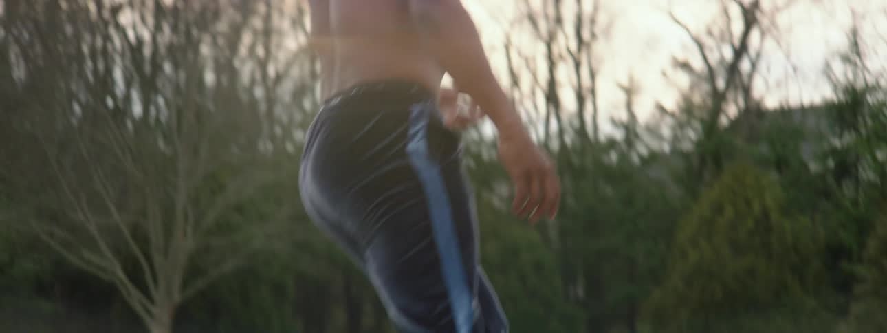 Shirtless young man rollerblading on path in the park during the day