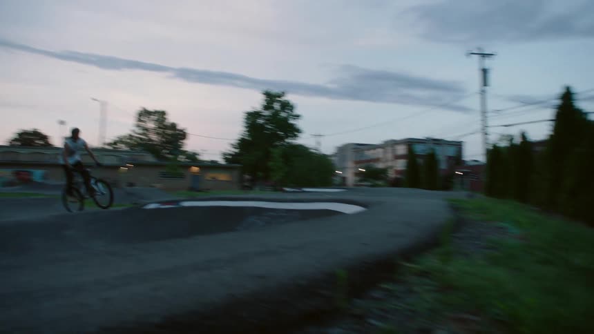 A cyclist rides a bicycle along the rough terrain on an outdoor bicycle course in the evening