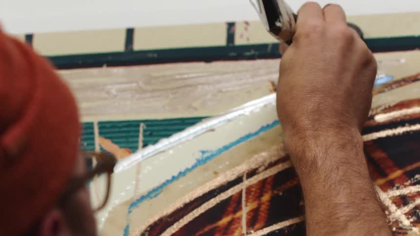 Man wearing beanie and glasses painting on canvas straight from the tube