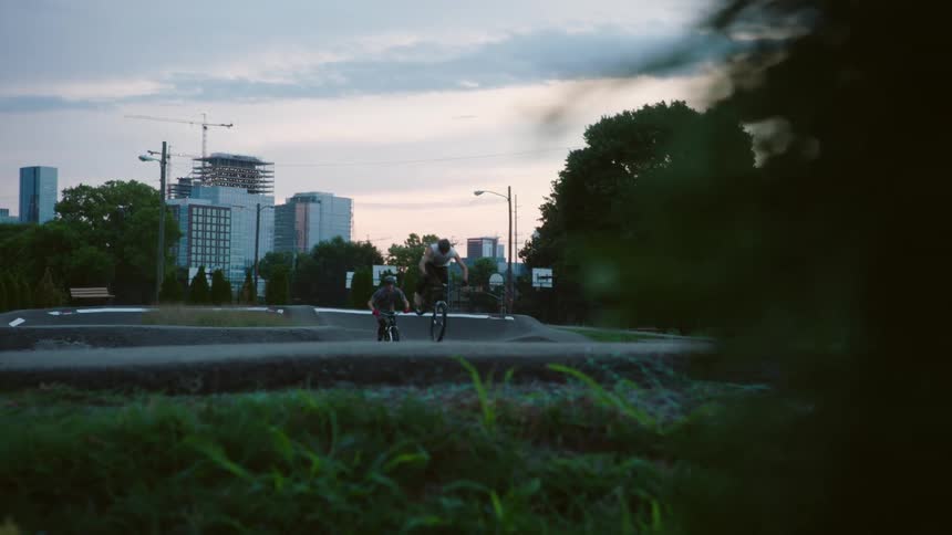 Two cyclist race along track with city skyline in the distance