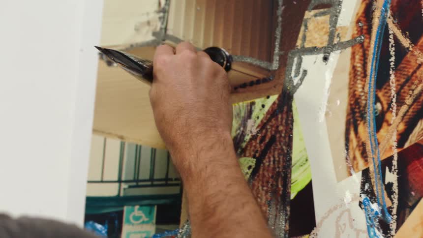 Close up of an artist painting on a large canvas with oils on a wall