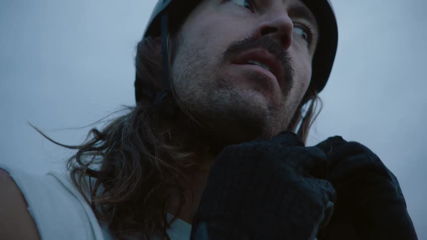 A close up of a man putting on a helmet wearing black gloves
