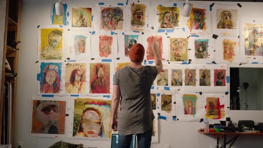 Artists counting the paintings hanging from a white wall