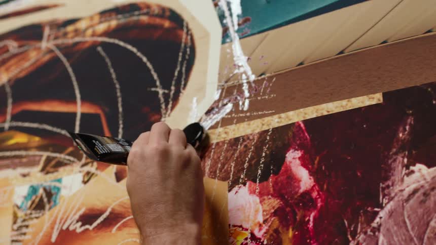 A man paints on canvas using paint directly from the tube