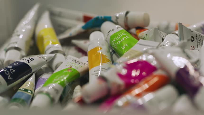 Close up of oil painting tubes piled up inside a plastic box