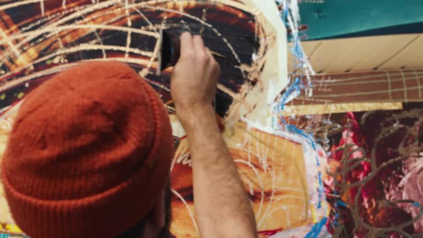 An artist using pants to create a piece of abstract artwork