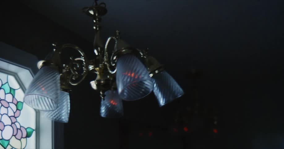 Close up of a lamp hanging from the ceiling turning on and off while swinging