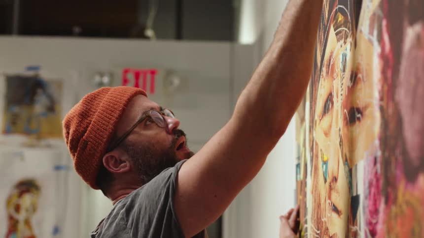 Close up of an artist painting a large oil painting on the wall of a museum