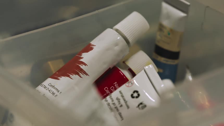 Paint tubes sit in plastic bin