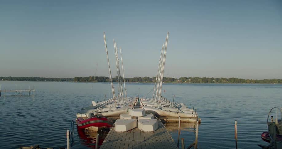 Group of small sailboats docked on a pier in a lake at evening