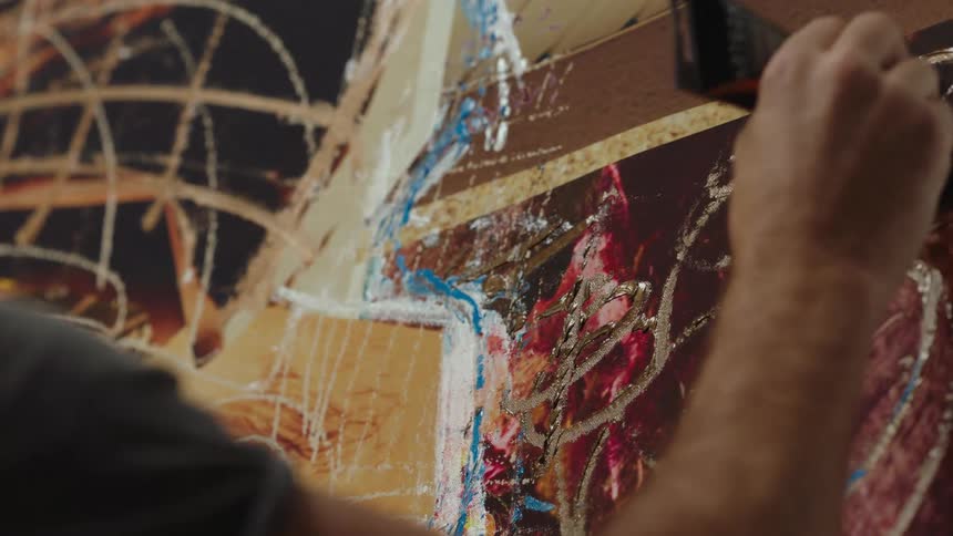 Close up of an artist painting on a large canvas with oils on a wall