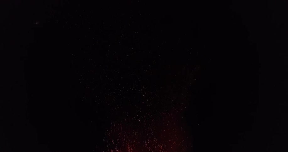 Glowing particles and sparks and a red cloud move up into the dark night sky