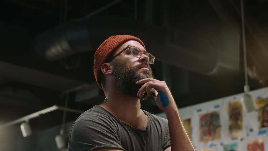 An up close of a man looking contemplatively with his hand on his chin
