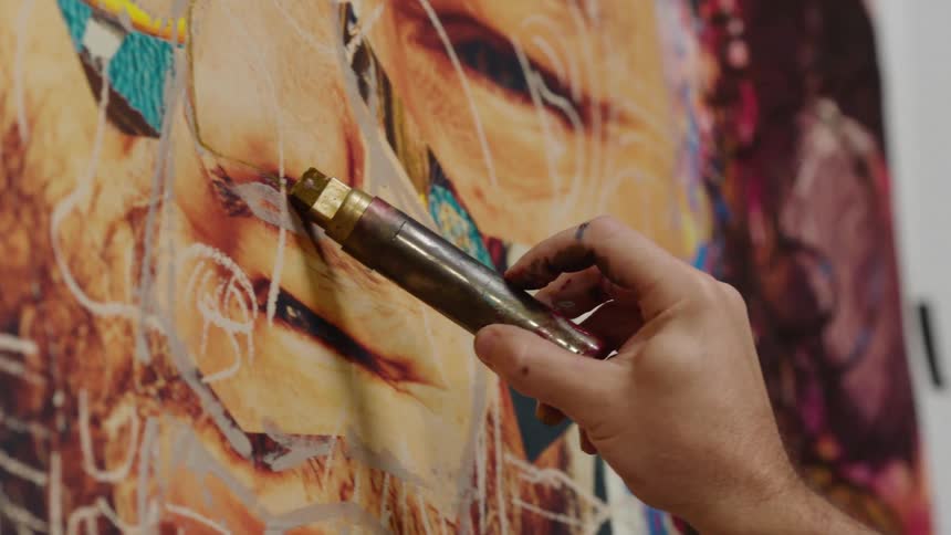 Close up of an artist painting on a large canvas with oils on a wall