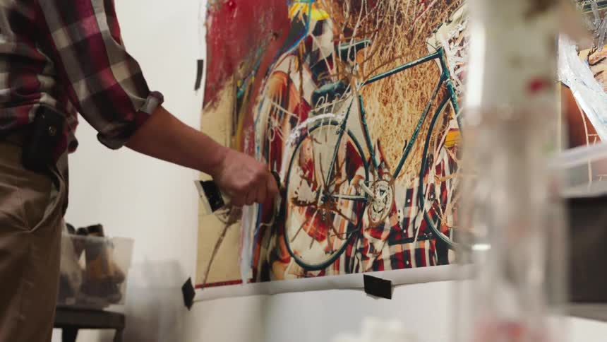 Close up of an artist painting on a large canvas with oils on a wall