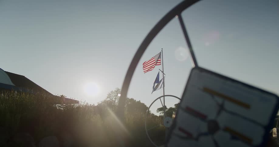 An up close of a wheel with flags blowing in the wind in the distance