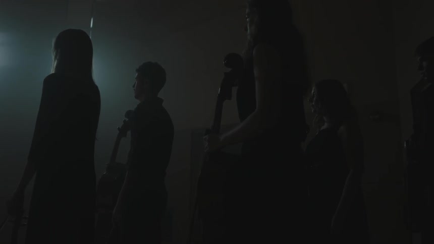 People stand together holding instruments in the dark
