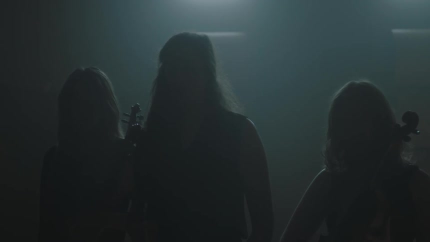 A group of musicians stand in a dark room