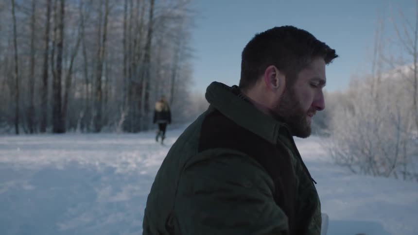 A man watches a woman walk away into snowy woods