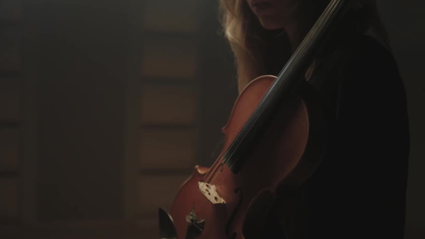 A woman stands holding a violin across her chest