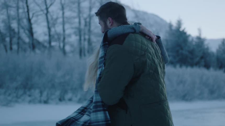 A man and woman twirl in the snow together