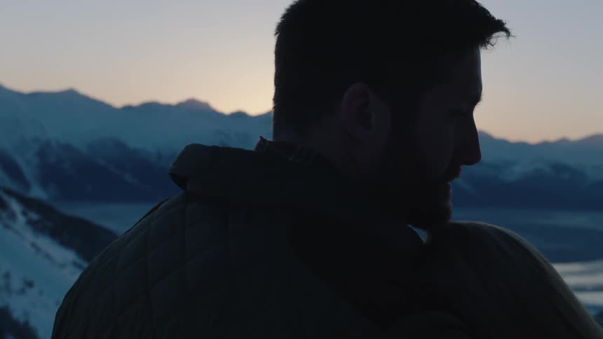 Two people are holding each other near a mountain range