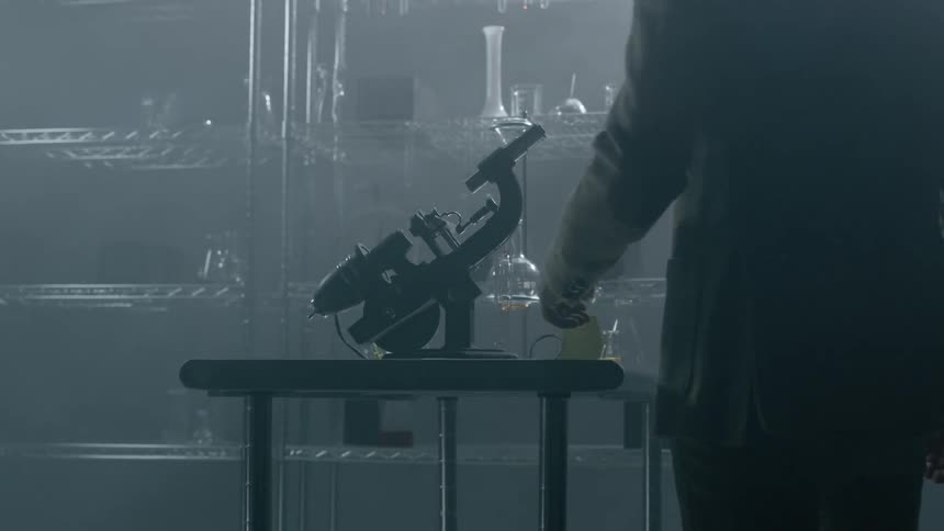 A man approaches and adjusts a microscope in a lab