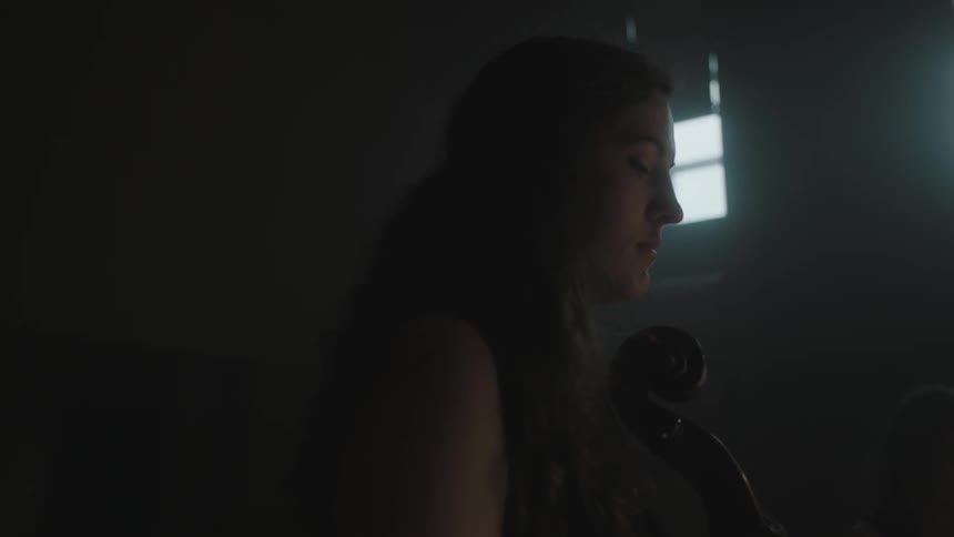 Women hold instruments in a dim room