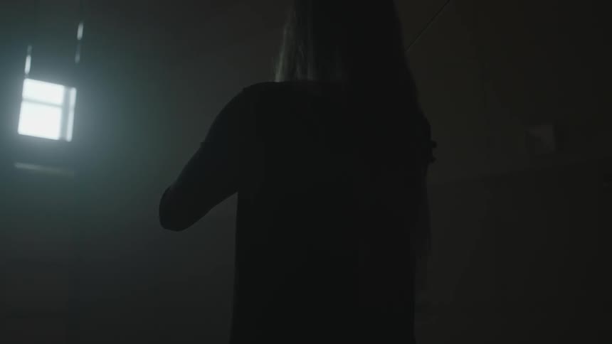 A violinist plays in a dim room