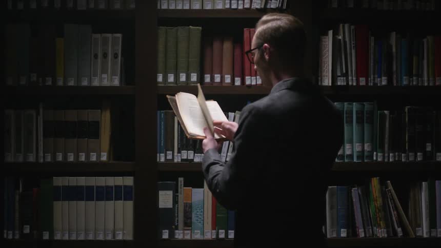 A man flips through a book in a library