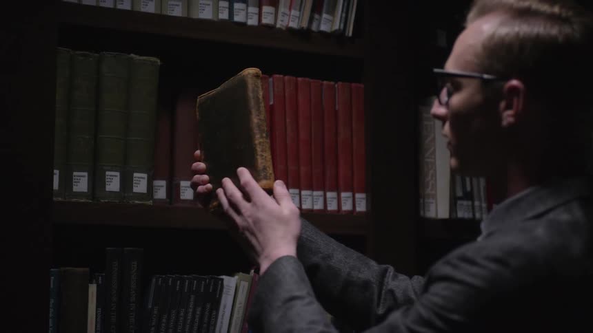Man takes a book from a bookshelf