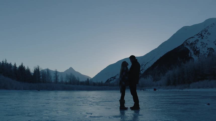 A man and woman stand on an icy pond