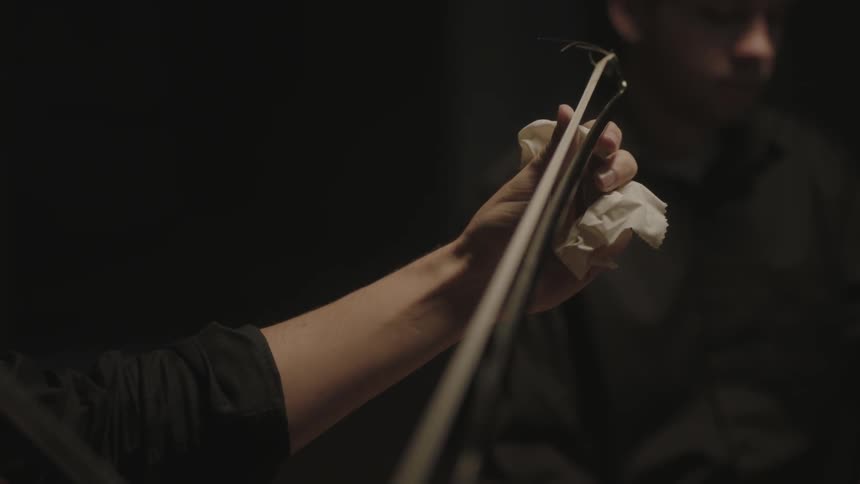 A person is polishing the stick from a musical instrument