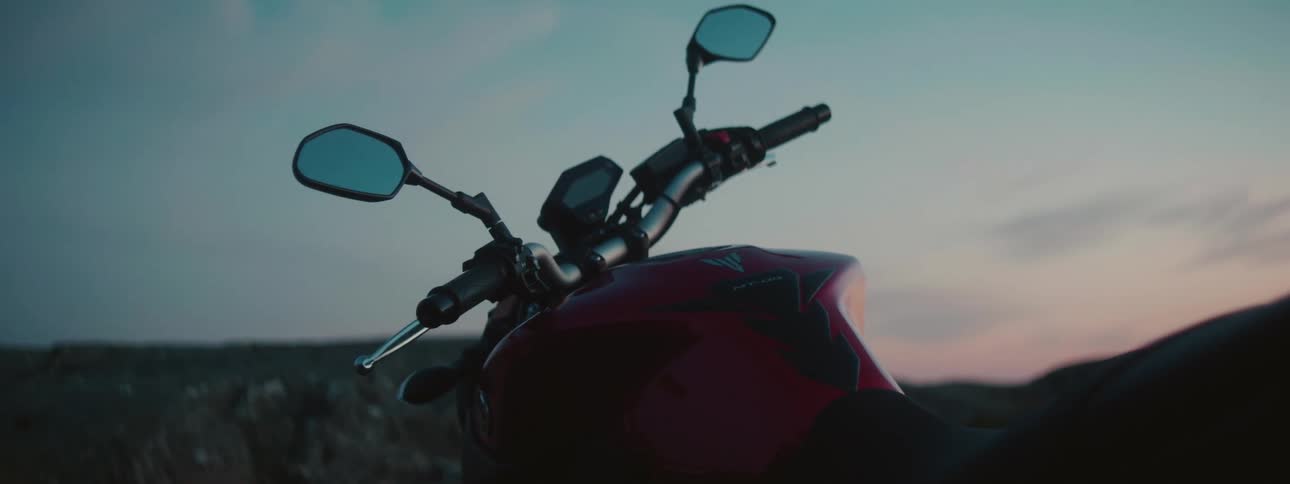 Red motorcycle stands in field under red sky