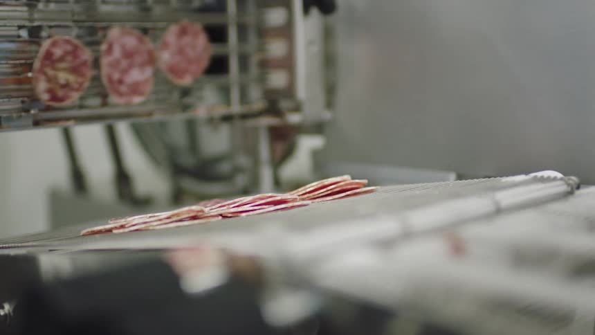 Salami coming out of a machine and laying down on a conveyor