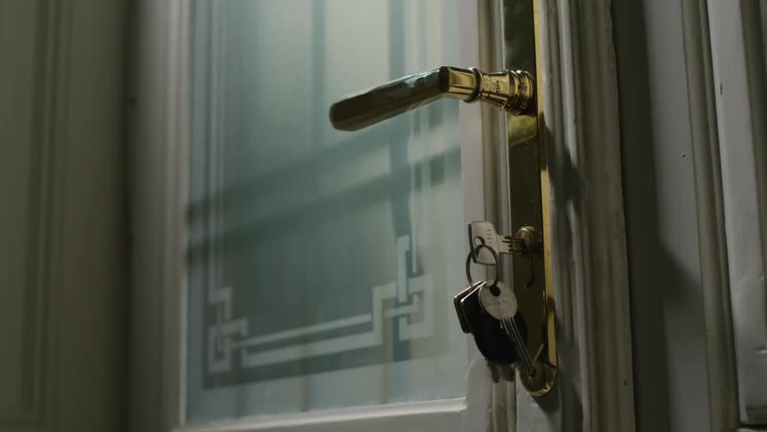 Person goes through door with keys in lock