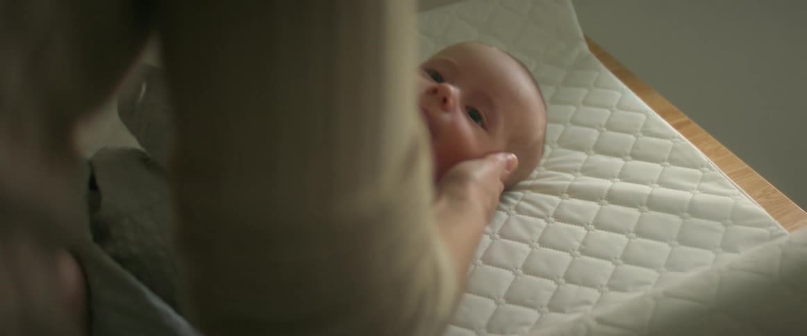 A person laying a baby on a changing pad