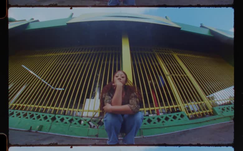 A woman is sitting near the yellow fence