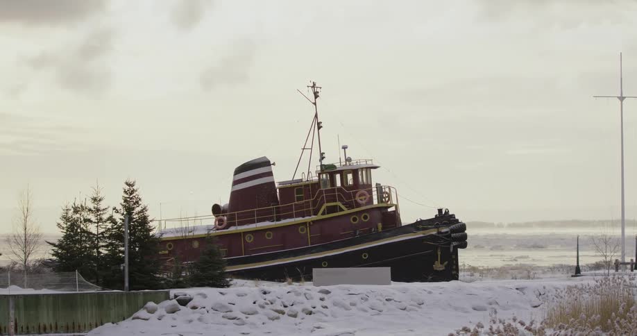 Red tugboat surrounded by snow at evening