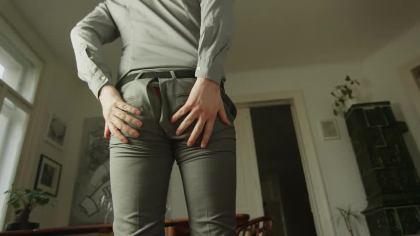 A man bending over and splitting his pants so red boxers show