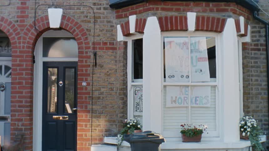 A handmade sign thanking employees hangs in the front window of a home
