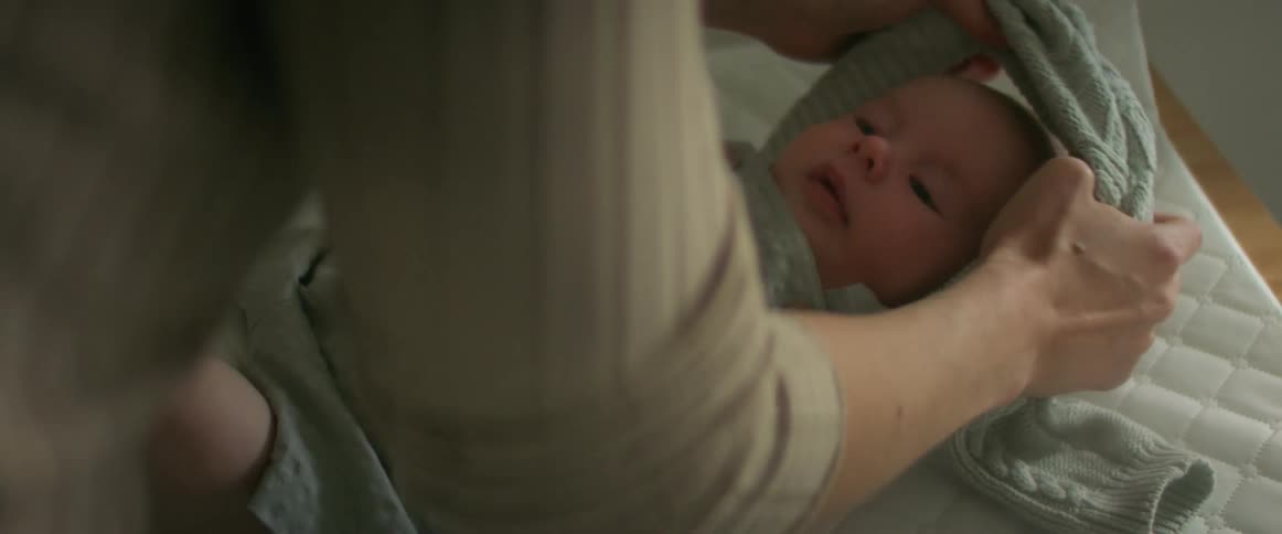 A woman changes her babys shirt on a table