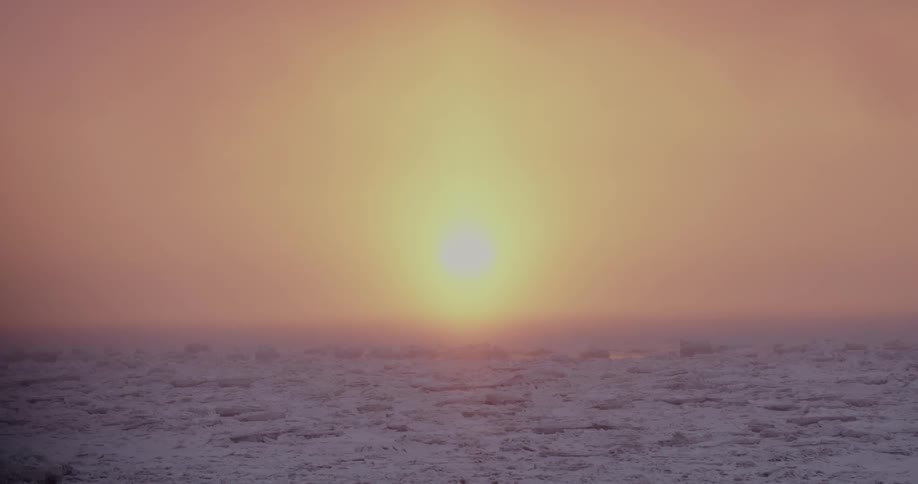 Sun setting over landscape of snowcovered flat grassland