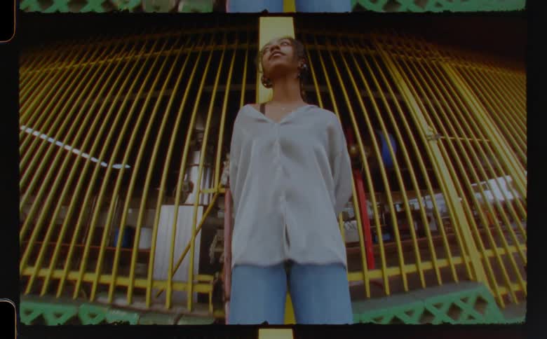 Woman stands near storefront with yellow painted bars