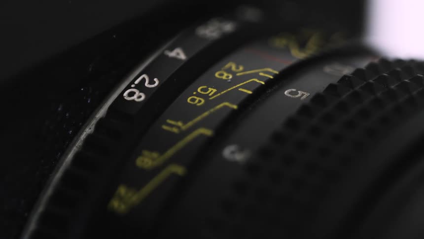 Close-up adjusting aputure dial on camera lens to control settings
